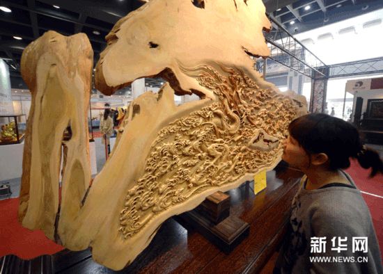 观众在浙江工艺美术精品展上参观《双龙戏珠》银杏木雕台屏.